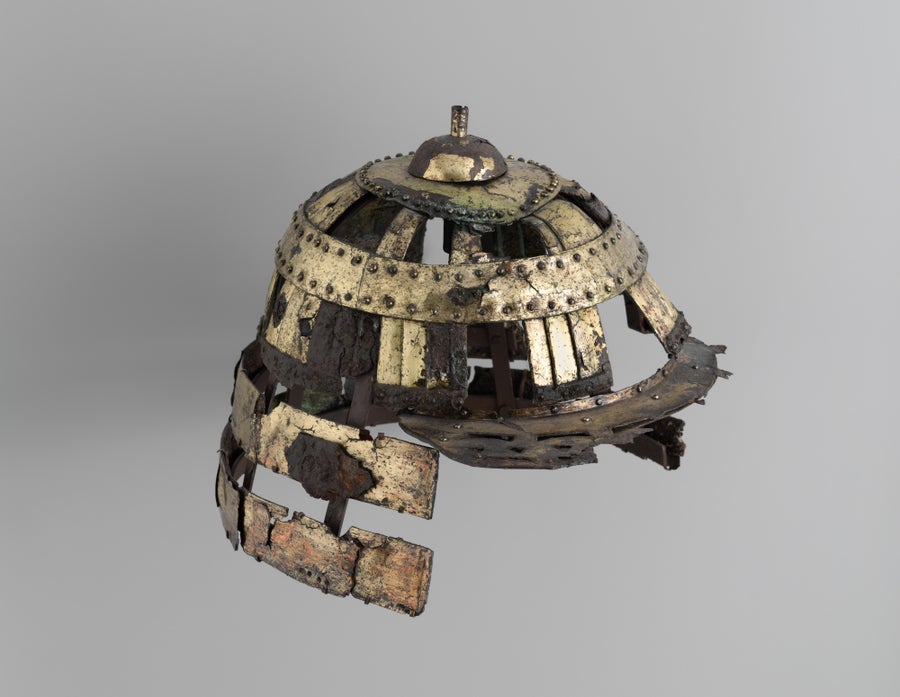 An aged robust and golden Japanese-style helmet, damaged pinch time.