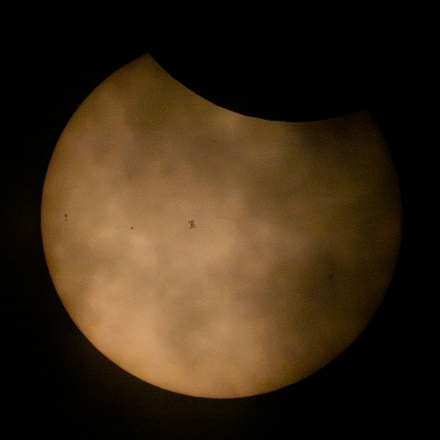 In this NASA handout, the Sun during a partial solar eclipse, partially obscured by clouds, the International Space Station, with a crew of seven onboard, is seen in silhouette as it transits at roughly five miles per second on August 12, 2026, near Hodgdon, Maine.