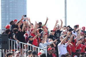 a large group of soccer fans in stadium stands with their hands in the air cheering