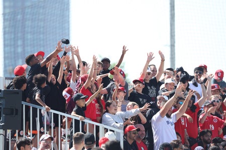 a large group of soccer fans in stadium stands with their hands in the air cheering