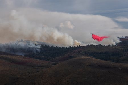 A firefighting aircraft drops fire retardant during the Hawk Fire on August 23, 2026, in Reno, Nev. The wildfire spread from the Sierra foothills toward Reno, forcing thousands to evacuate their homes. Officials said the fire was human-caused.