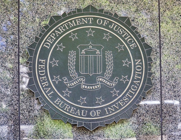 A gray emblem on a dark stone wall.