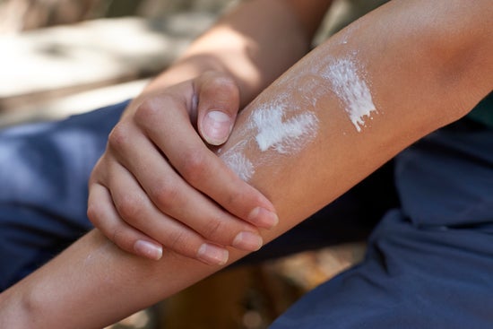 Teenage boy applying sunscreen during hiking day