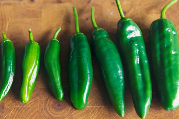 Homegrown jalapeño peppers on a wooden chopping board.