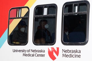 Passengers wearing masks seen through darkened bus windows