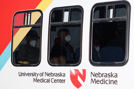 Passengers wearing masks seen through darkened bus windows