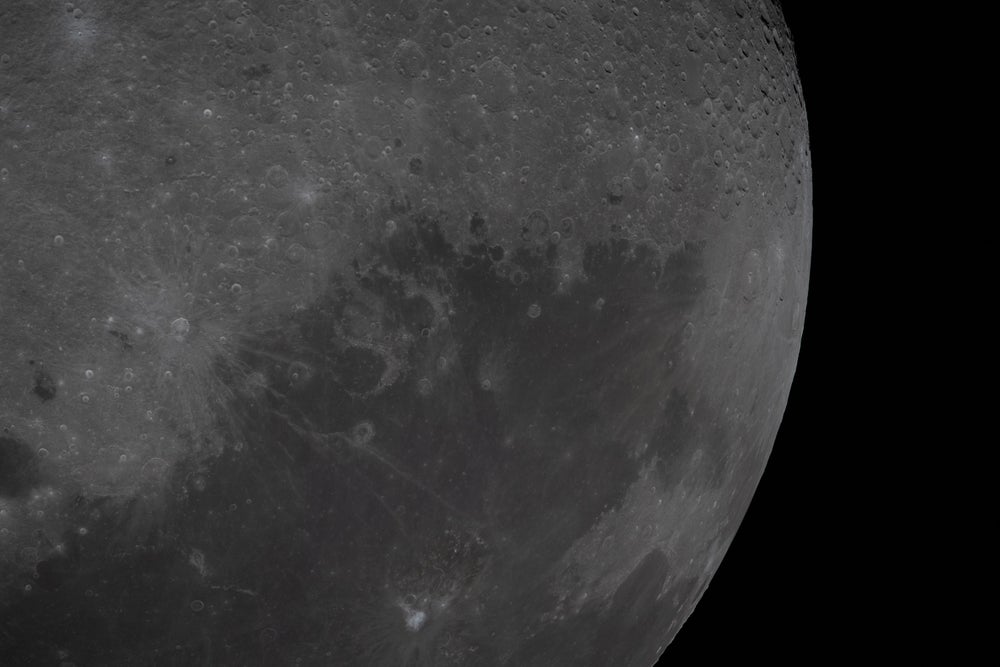 Una vista de la superficie lunar con una gran mancha de terreno oscuro visible.