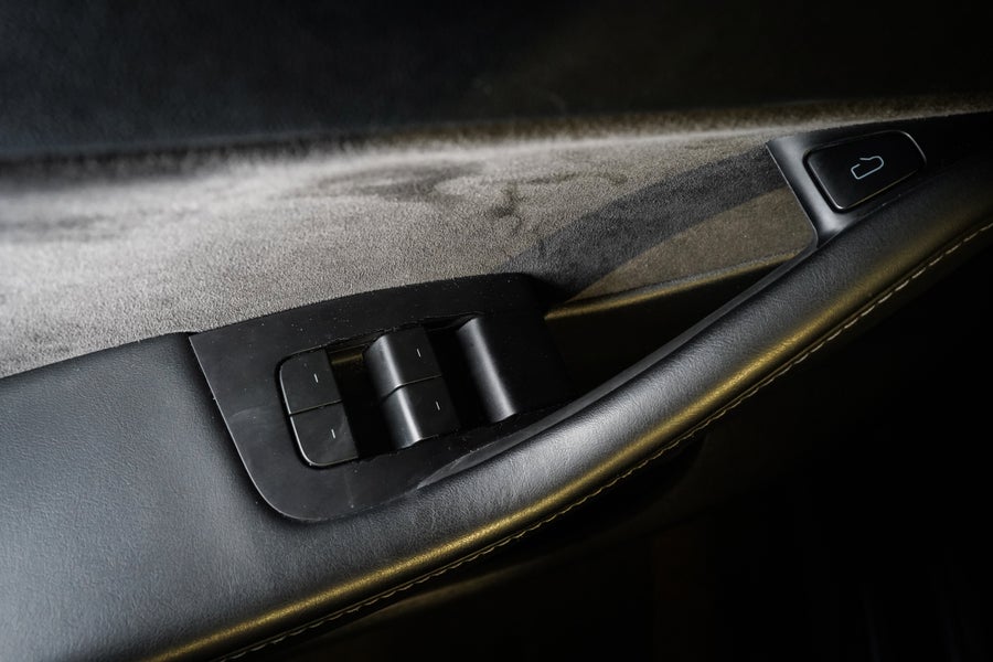 Tesla front-door controls with an electronic open button and a separate manual-release lever beside the window switches.