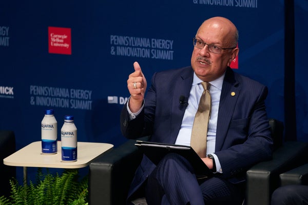 Farnam Jahanian sitting in a suit against a Pennsylvania Energy and Innovation Summit background.