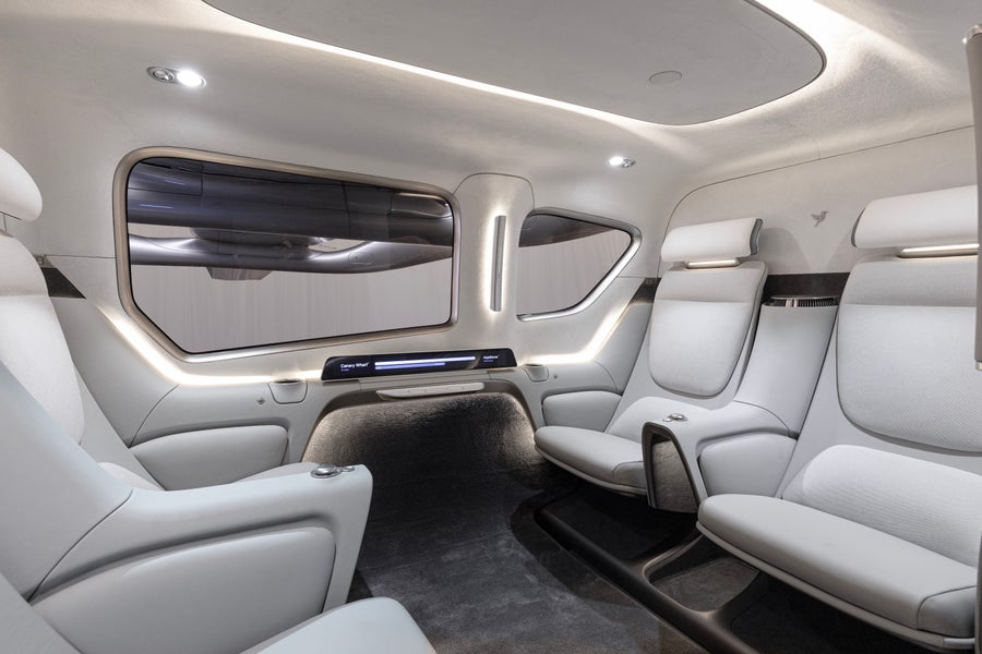 The Valo cabin interior has four light-colored passenger seats, large windows and soft lighting.