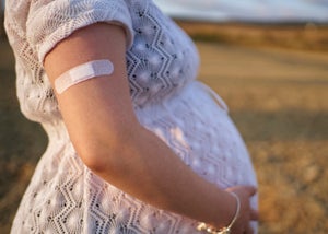 A pregnant woman with a bandaid on her shoulder.