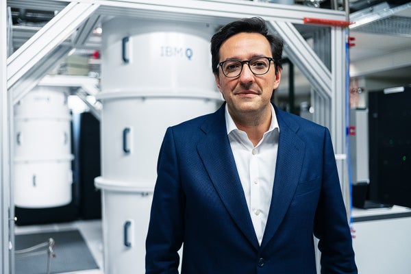 Darío Gil in a blue suit, standing in front of IBM technology.