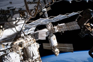 A series of modules and solar panels orbit in space above the curve of Earth’s horizon.