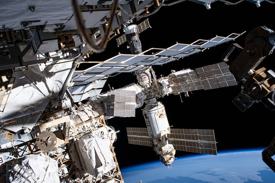 A series of modules and solar panels orbit in space above the curve of Earth’s horizon.