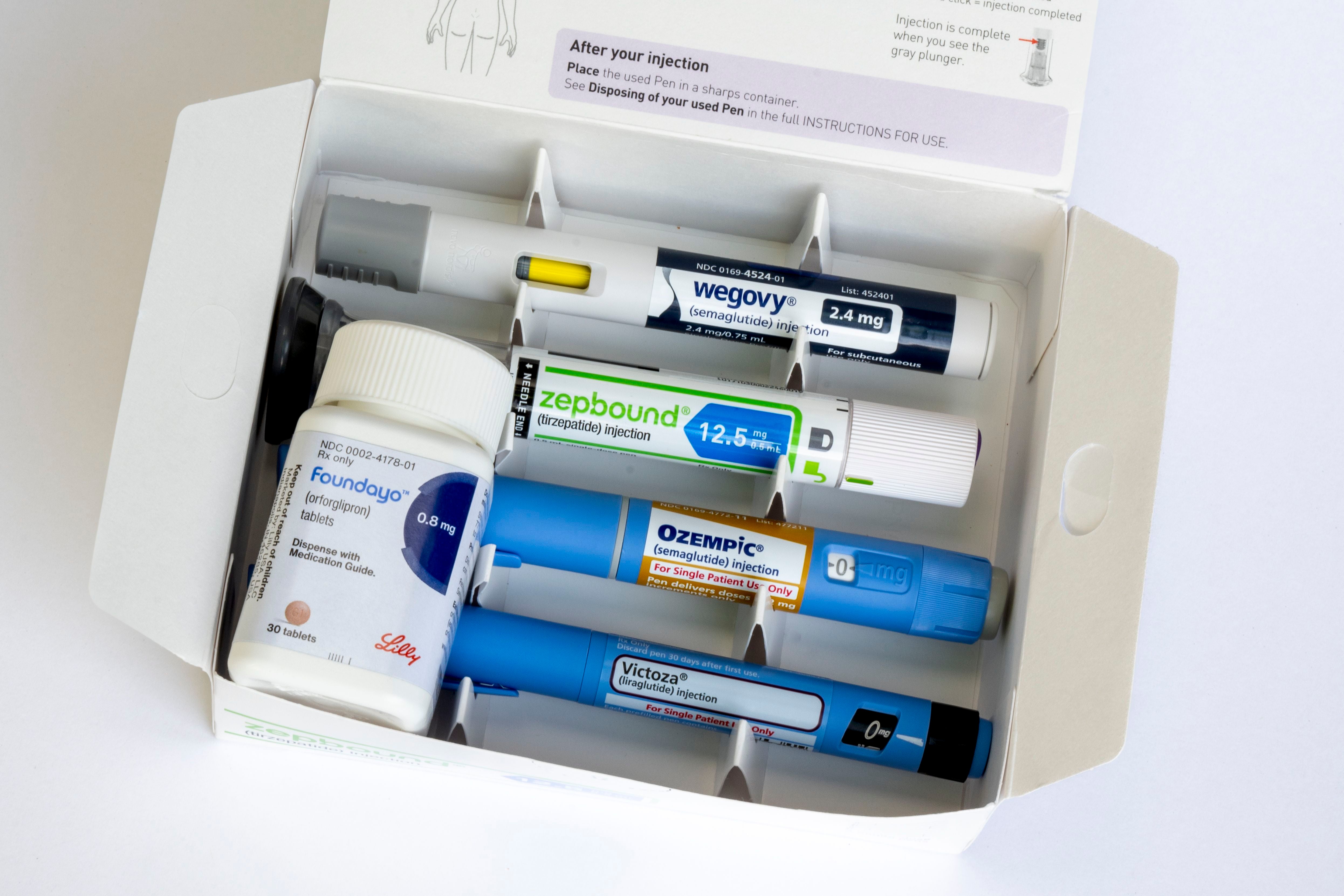 Photo illustration of a group of weight loss medications on a white background.