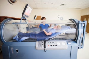 Patient lying in a hyperbaric chamber with technician in background