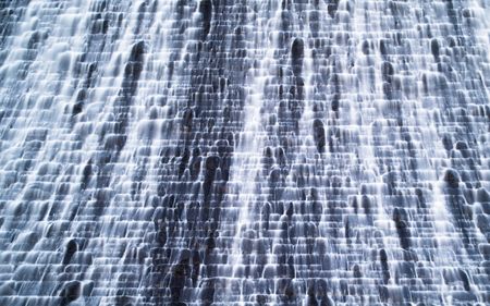 A wall of water falls along a cascading, seemingly human-made path.