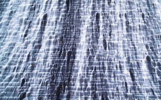 A wall of water falls along a cascading, seemingly human-made path.