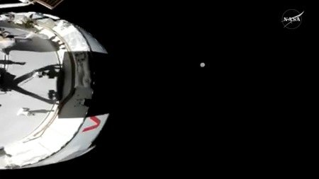 A pixelated live image of the Orion spacecraft from the outside, with the moon visible in the distance ahead.