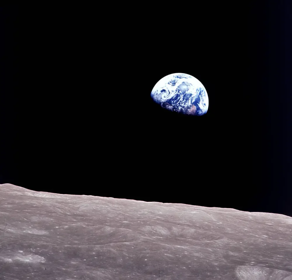 Se ve una Tierra gibosa flotando sobre una superficie lunar gris y austera.