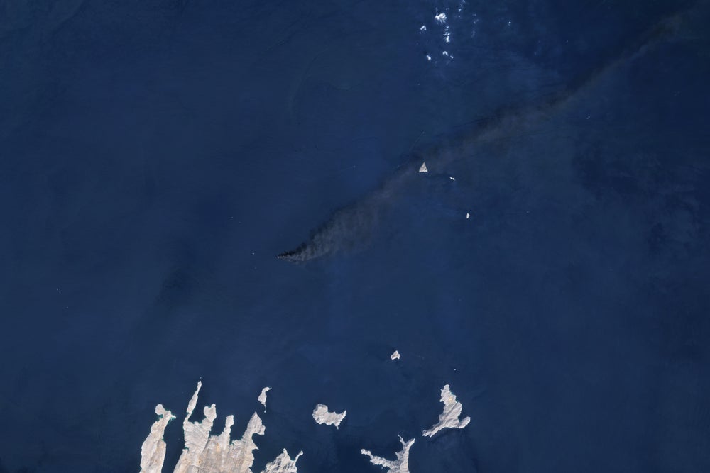 Una columna de color gris oscuro sobre aguas azules vista desde arriba.