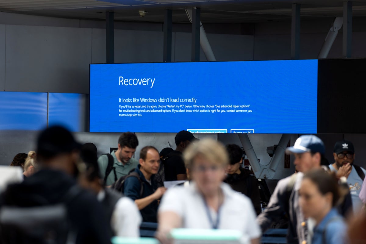 Blue Recovery screen at airport with travellers in foreground