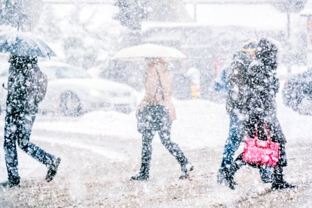 People walking across a road as heavy snow falls