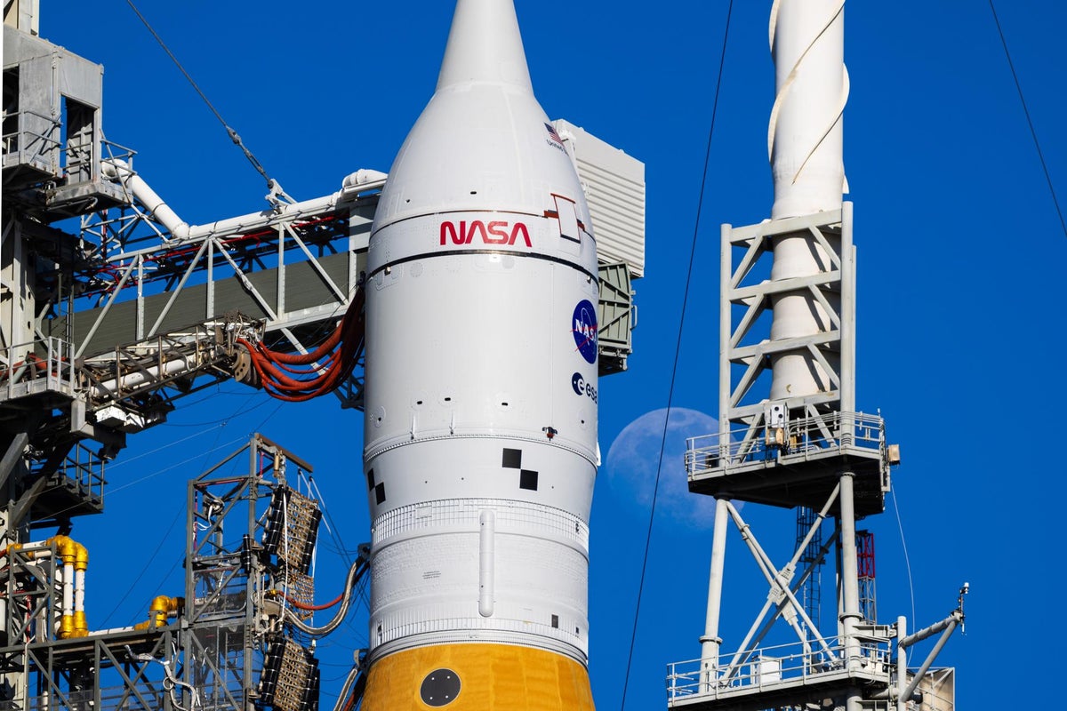 The moon is seen shining next to the SLS (Space Launch System) and Orion spacecraft atop the mobile launcher on January 28, 2026, at Launch Pad 39B at NASA's Kennedy Space Center in Florida.
