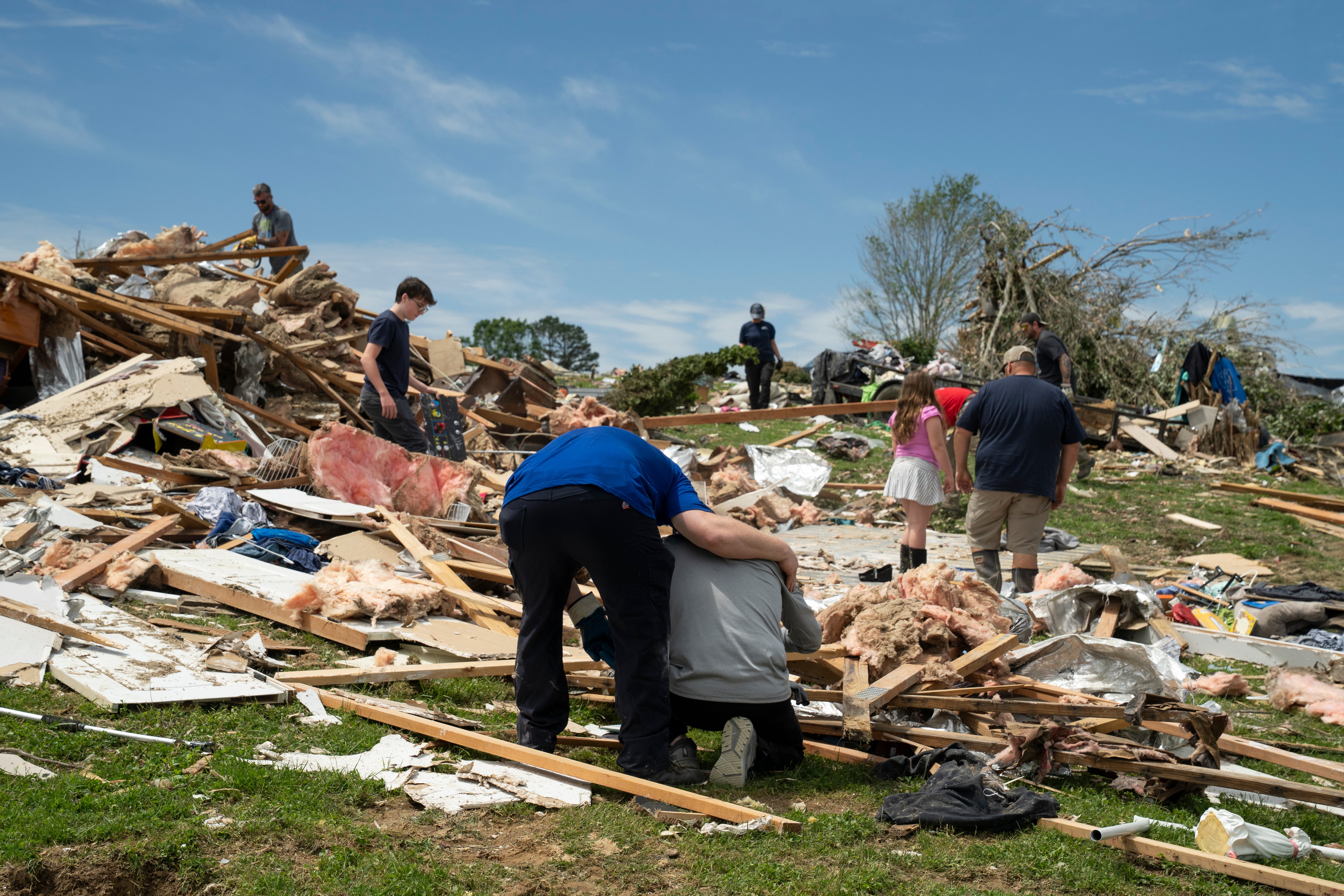 Man kneeling in front of his destroyed home.