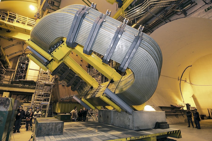 Workers at CERN stare upwards at the comparatively large LHCb particle detector magnet