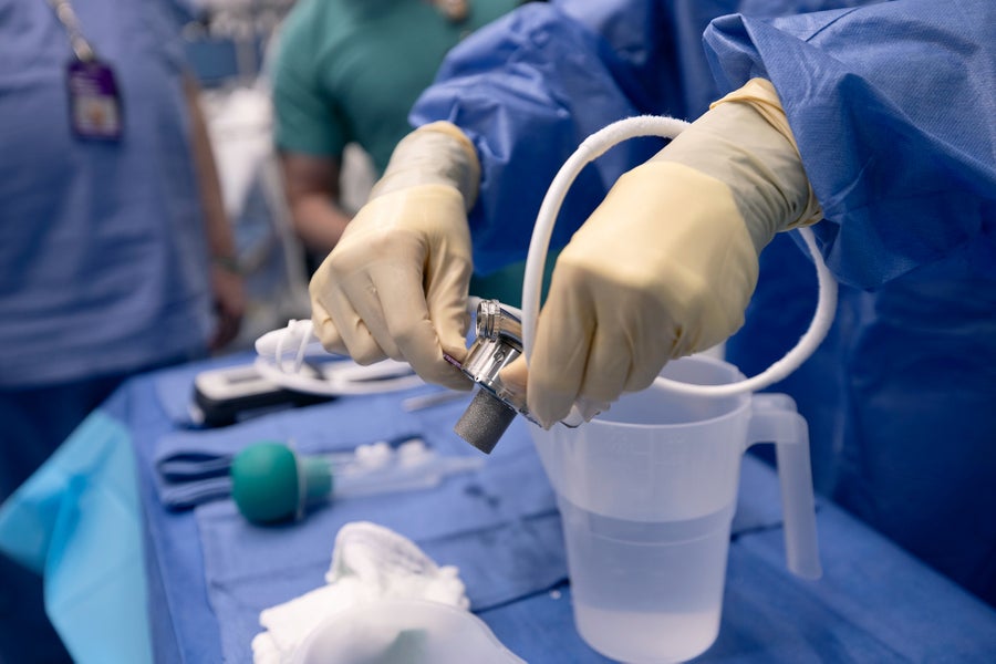 Gloved hands holding a medical device in an operating room