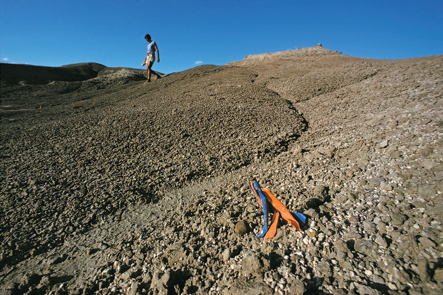 A rugged desert landscape, with one person walking down a sandy hill