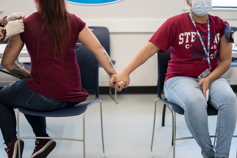 Workers hold hands while receiving Covid vaccine