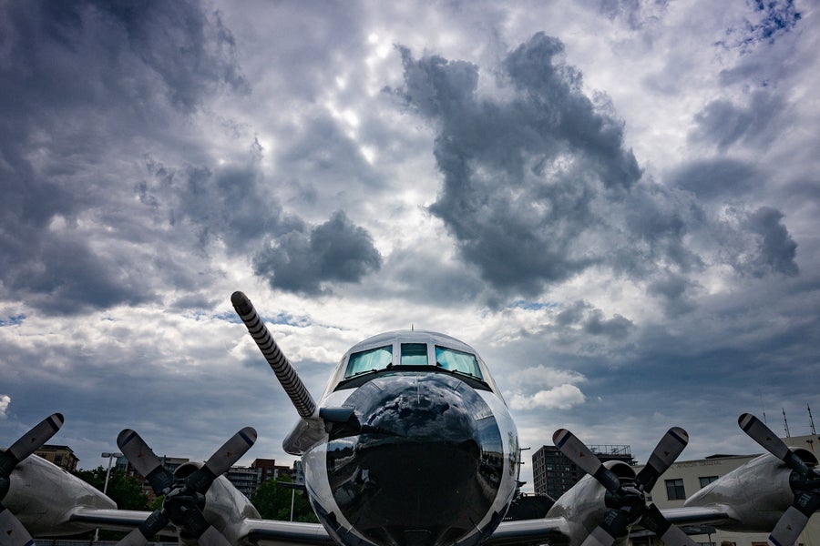 A hurricane hunter plane seen head-on with cloudy skies in the background