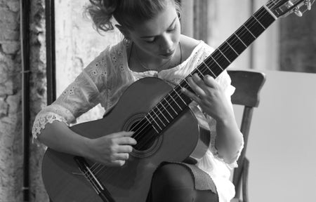 Black and white photo of woman playing classical guitar