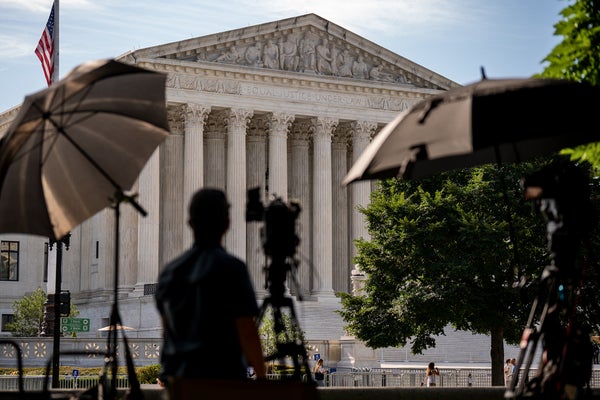 Silhouetted in the foreground a member of the media sets up near the US Supreme Court building, seen in focus in the background