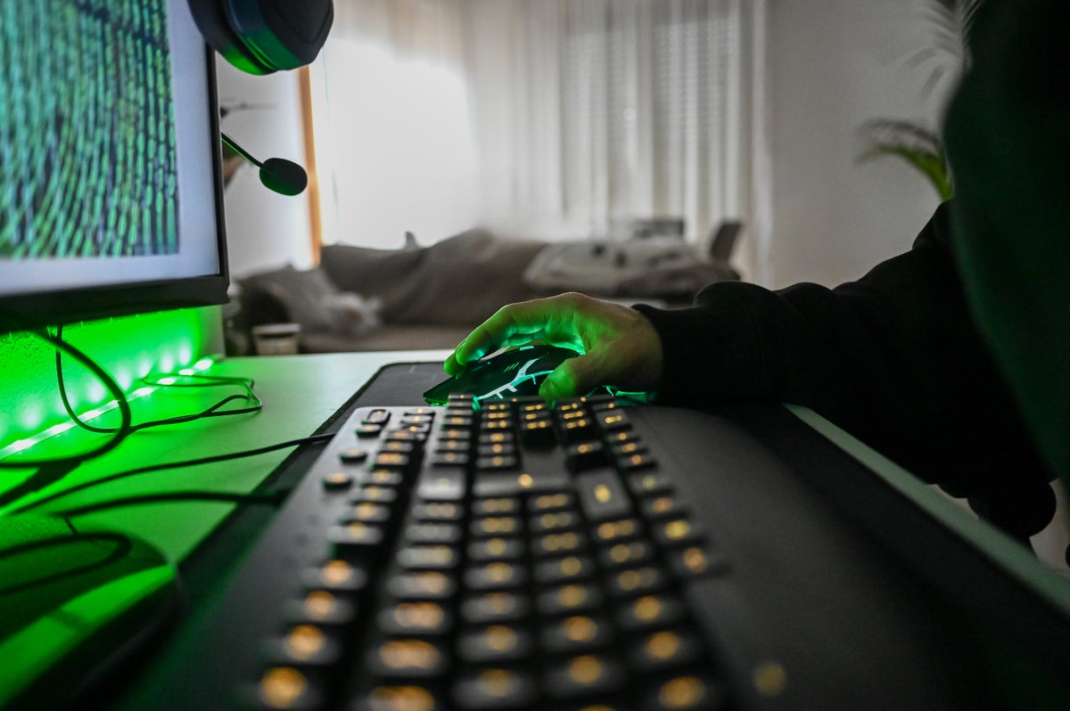 Person playing video game on computer with neon green lighting