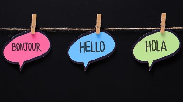 Three paper cut-outs in the shape of speech bubbles read bonjour, hello and hola