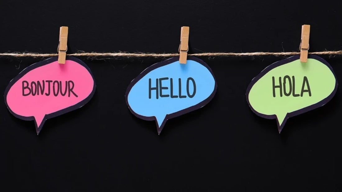 Three paper cut-outs in the shape of speech bubbles read bonjour, hello and hola