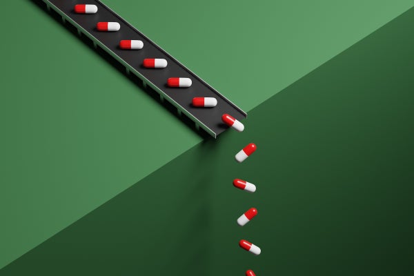 Conveyor belt with pills dropping the pills over an edge with green background, illustrating new medical treatments in the works.