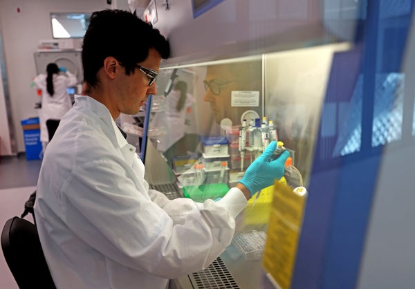 A man in a white lab coat and blue gloves