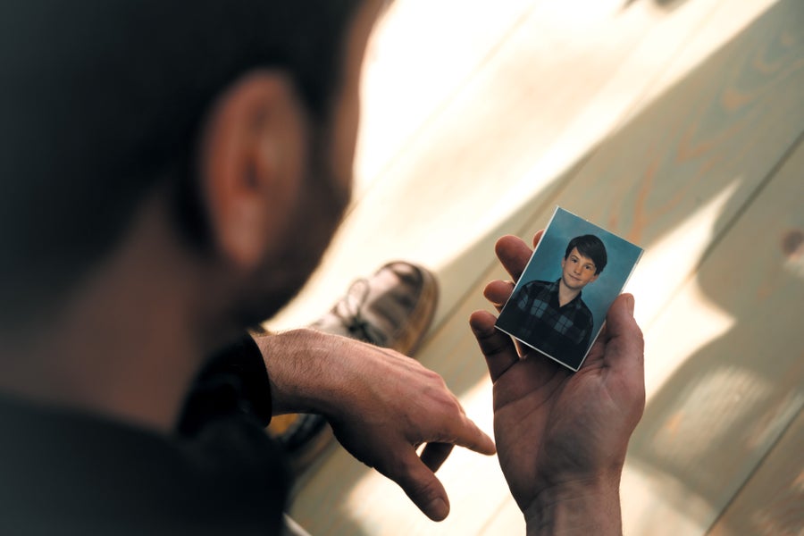 Man holding a small photograph of a young boy