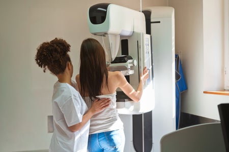 Stock photo depicting a medical professional assisting a young patient during a mammography test in examination room