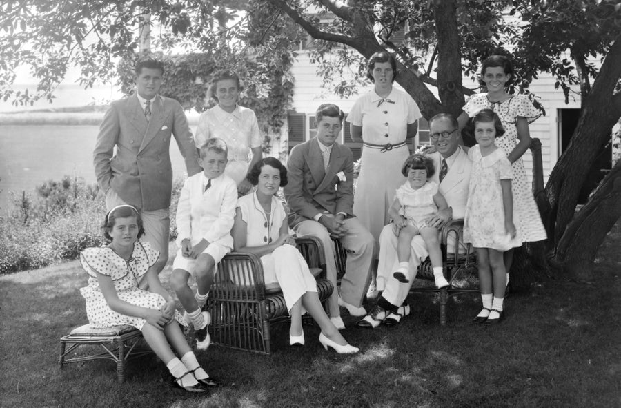 Black and white photo of the Kennedy family sitting under the shade of some trees