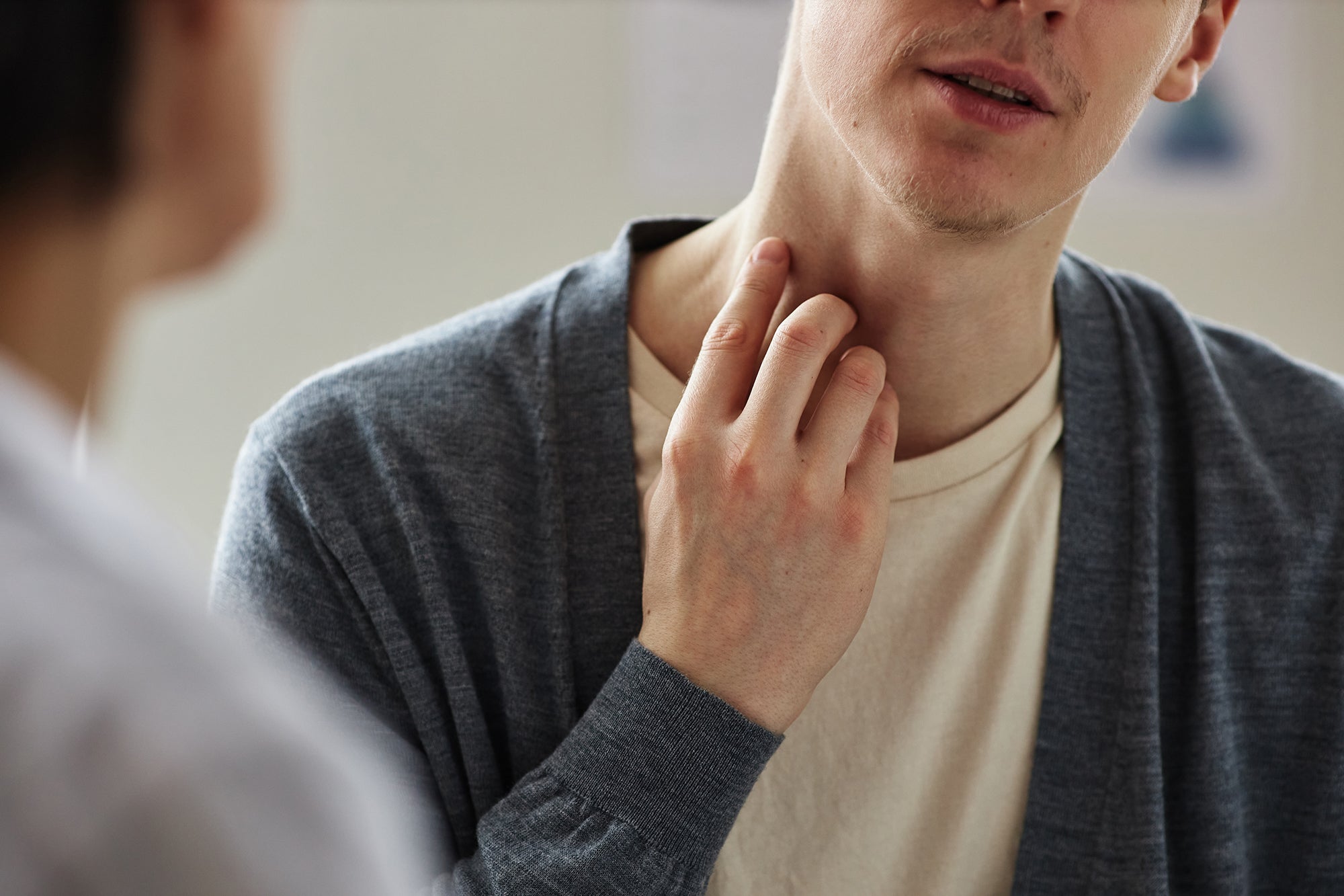 Close up of man scratching neck while talking to another person