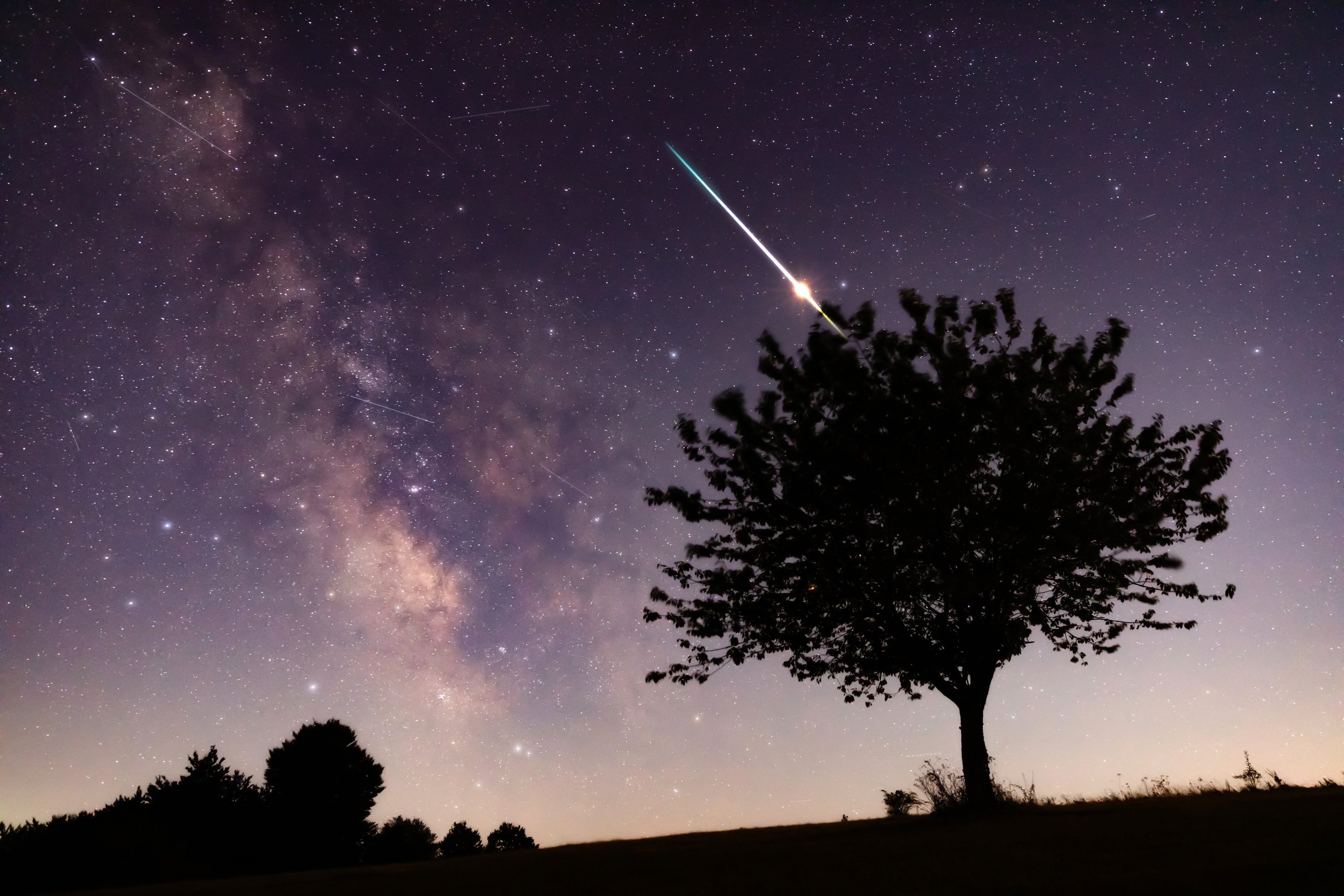 Star-filled night sky with bright meteor streaks overhead