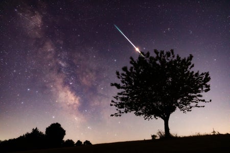 Star-filled night sky with bright meteor streaks overhead