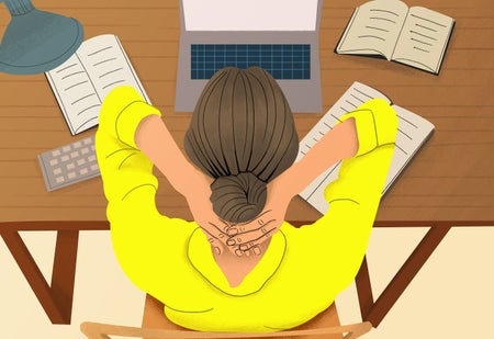 High angle view tired businesswoman with hands behind head working at desk with a laptop, papers, and open books