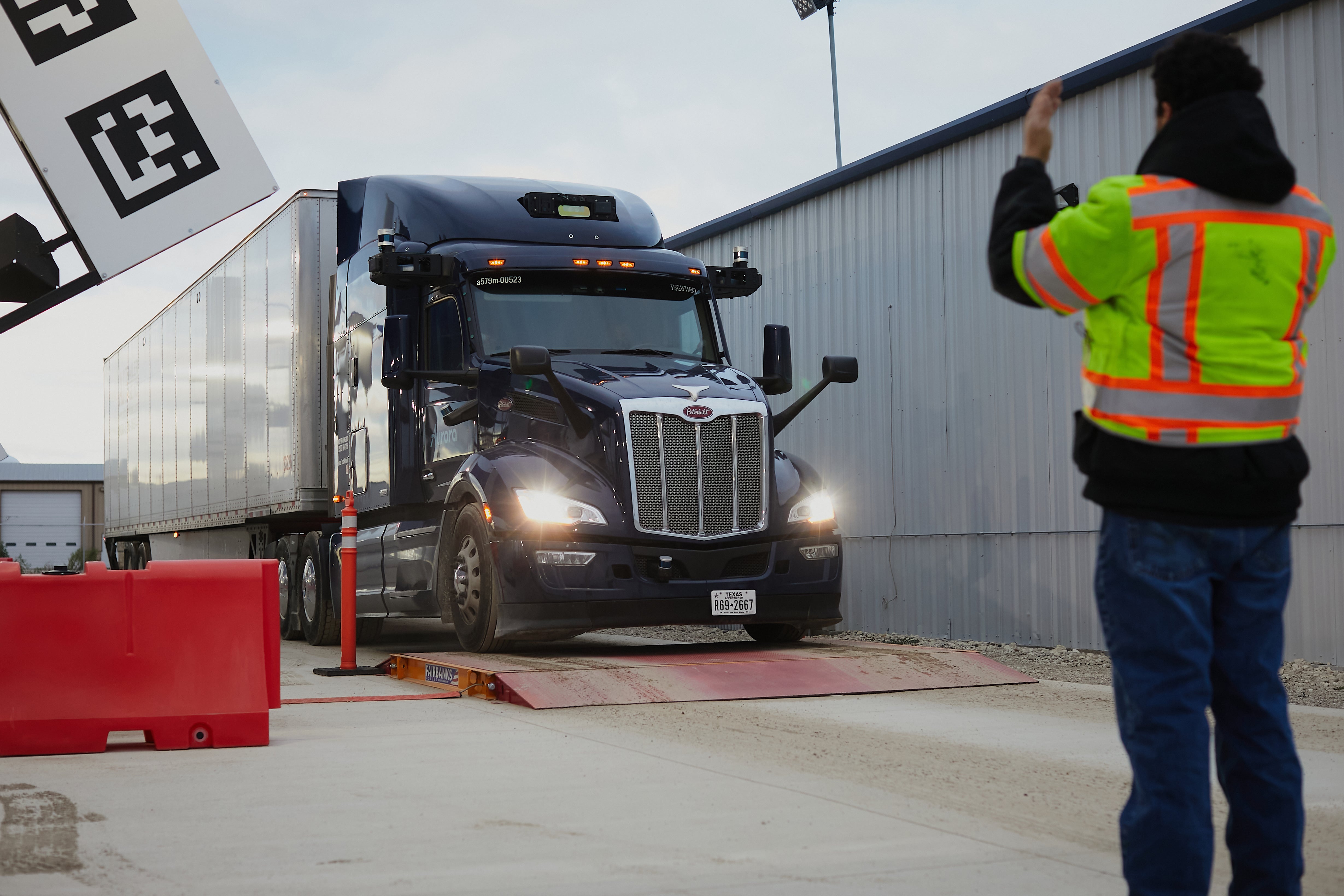 A worker directs an Aurora Innovation Inc. driverless truck