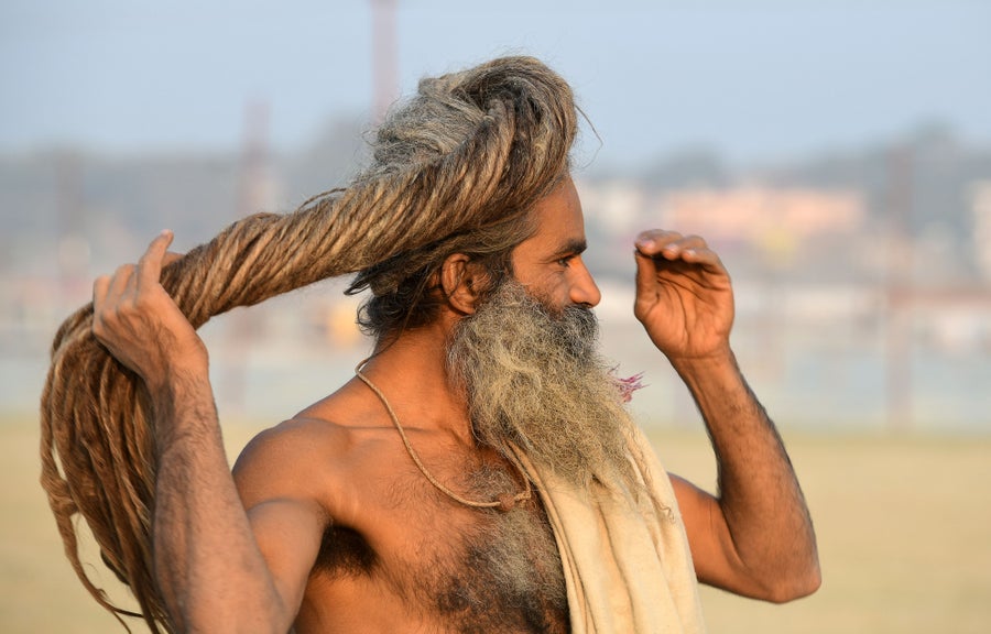 A man gathers and twists his long dreadlocks in his hand